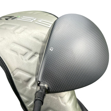 Mega Golf Taylormade Qi35 LS driver with carbon fiber face and silver headcover on green grass.